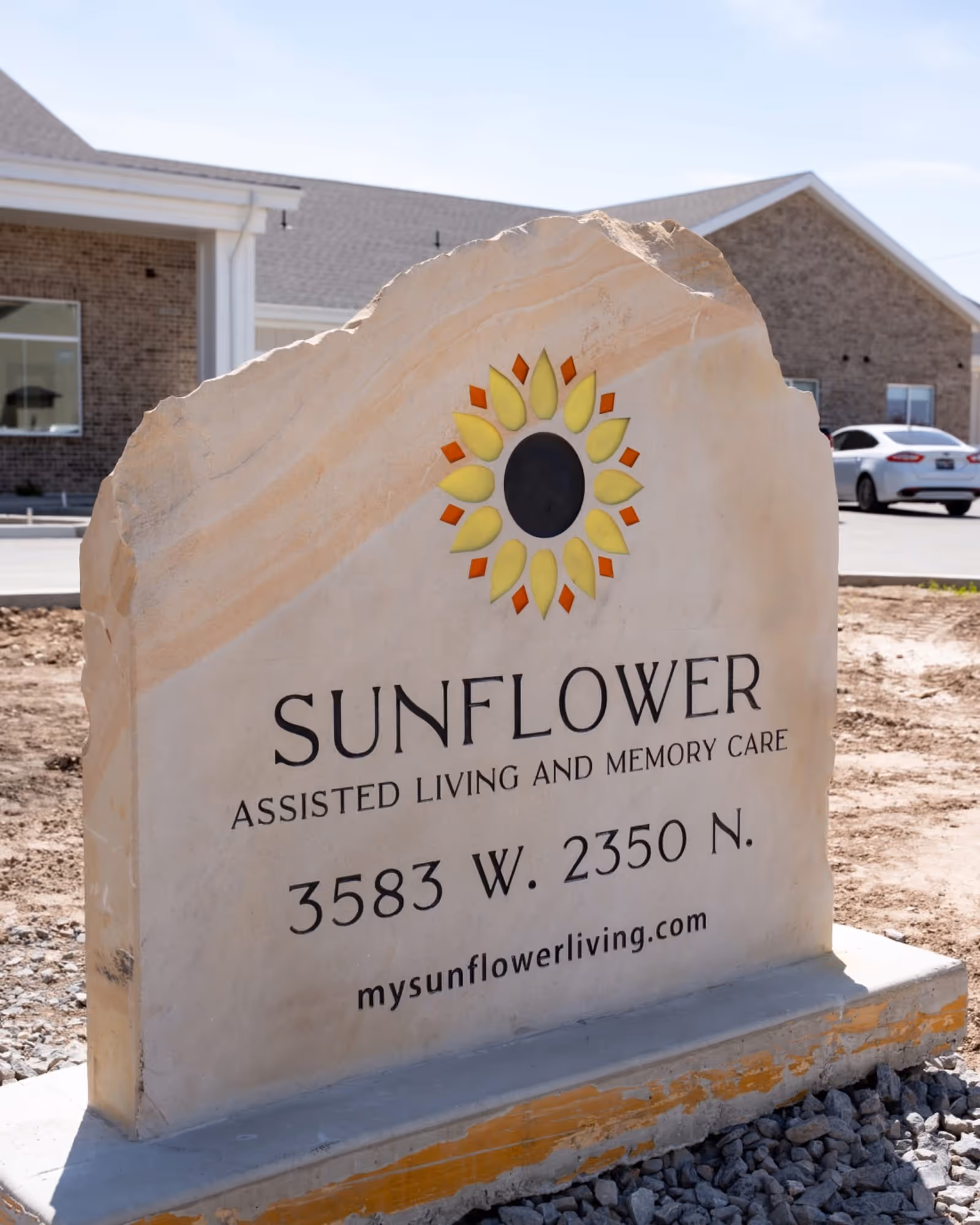 Stone sign reading Sunflower Assisted Living and Memory Care with a building in the background