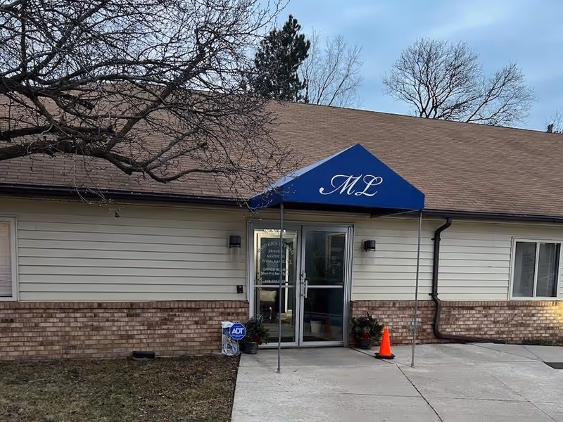 Exterior of Modern Living Assisted Living for Seniors facility, entrance with blue awning and glass doors.