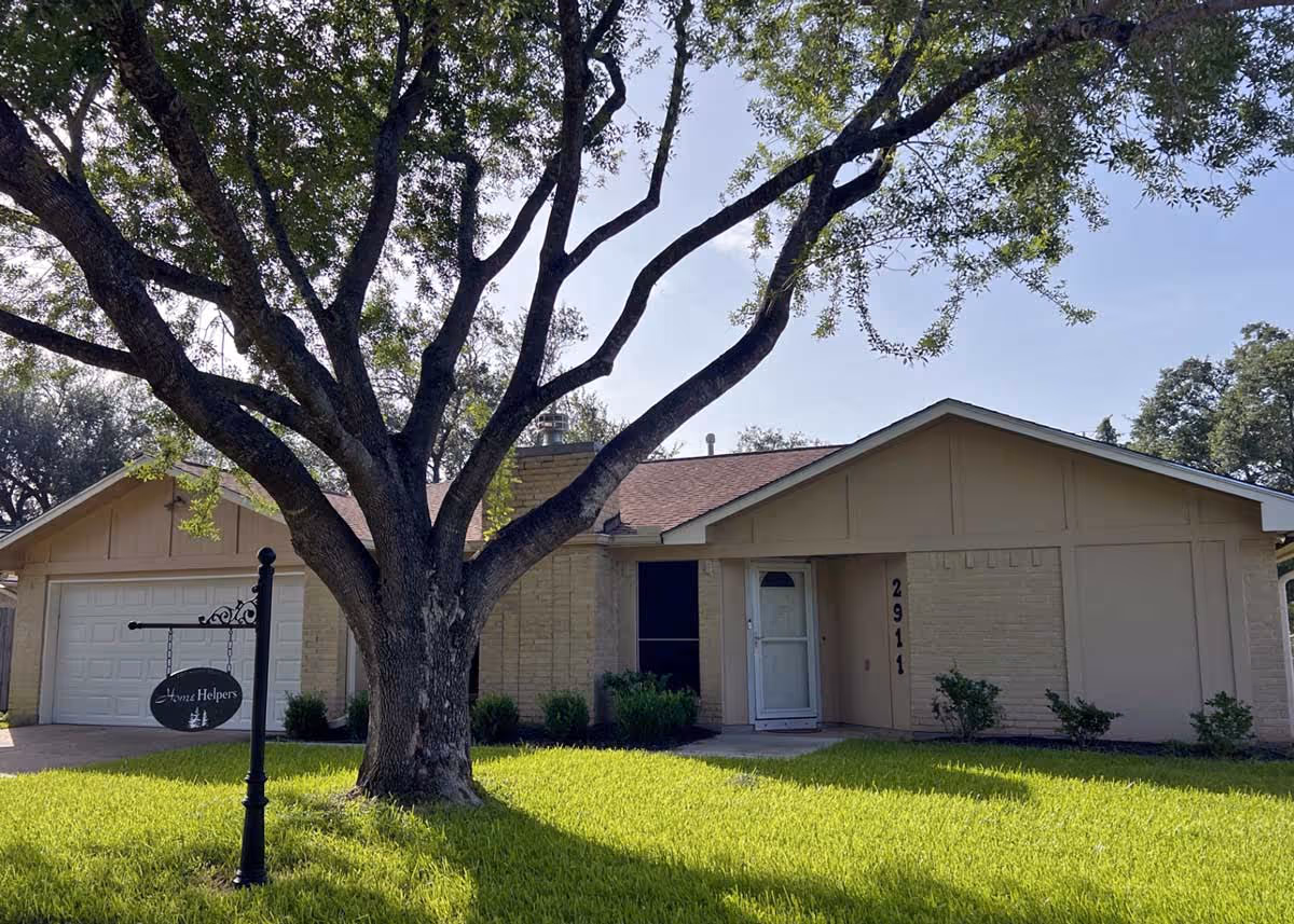 A residential-style building front with a large tree and a Home Helpers sign.
