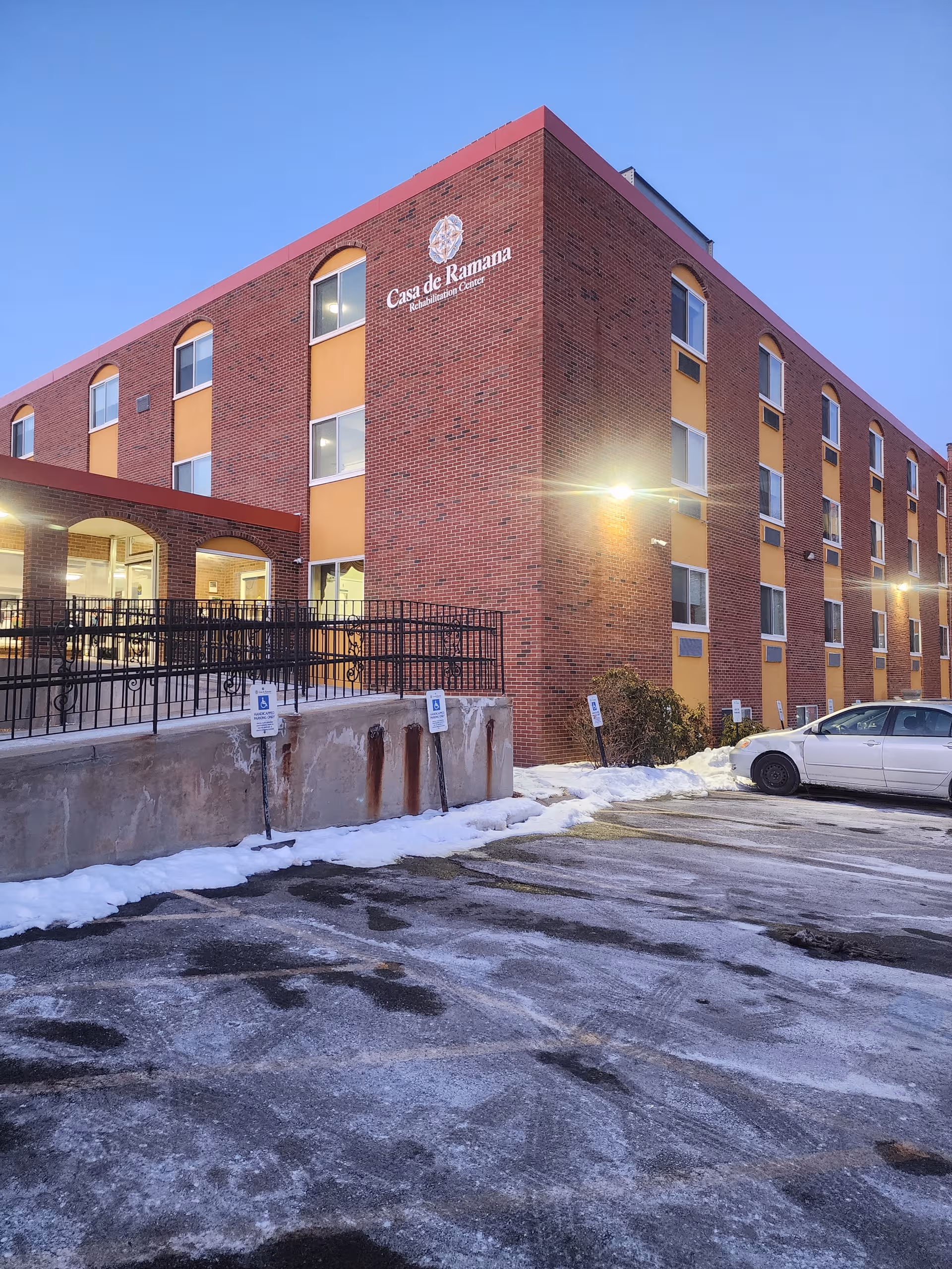 Red brick rehabilitation center building with Casa de Ramana sign and snow-covered parking lot