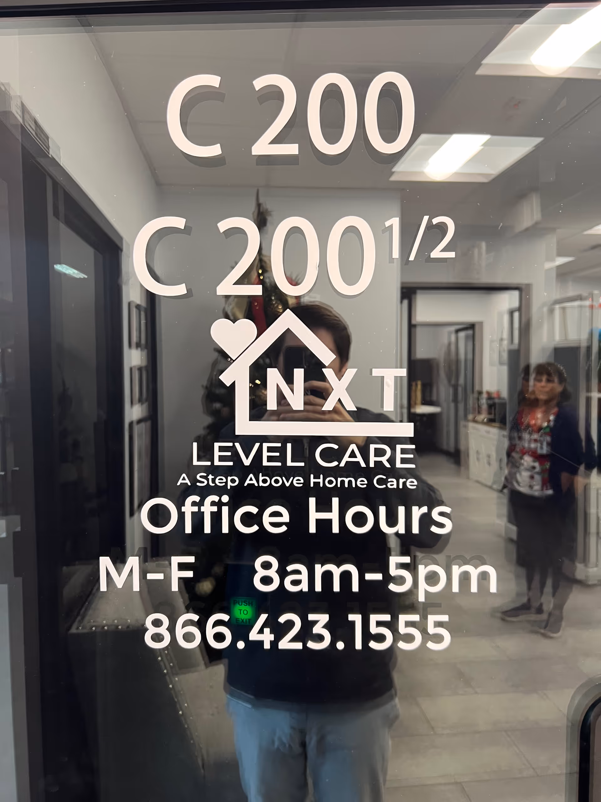 Glass door with white signage for Nxt Level Care, reflecting a hallway.