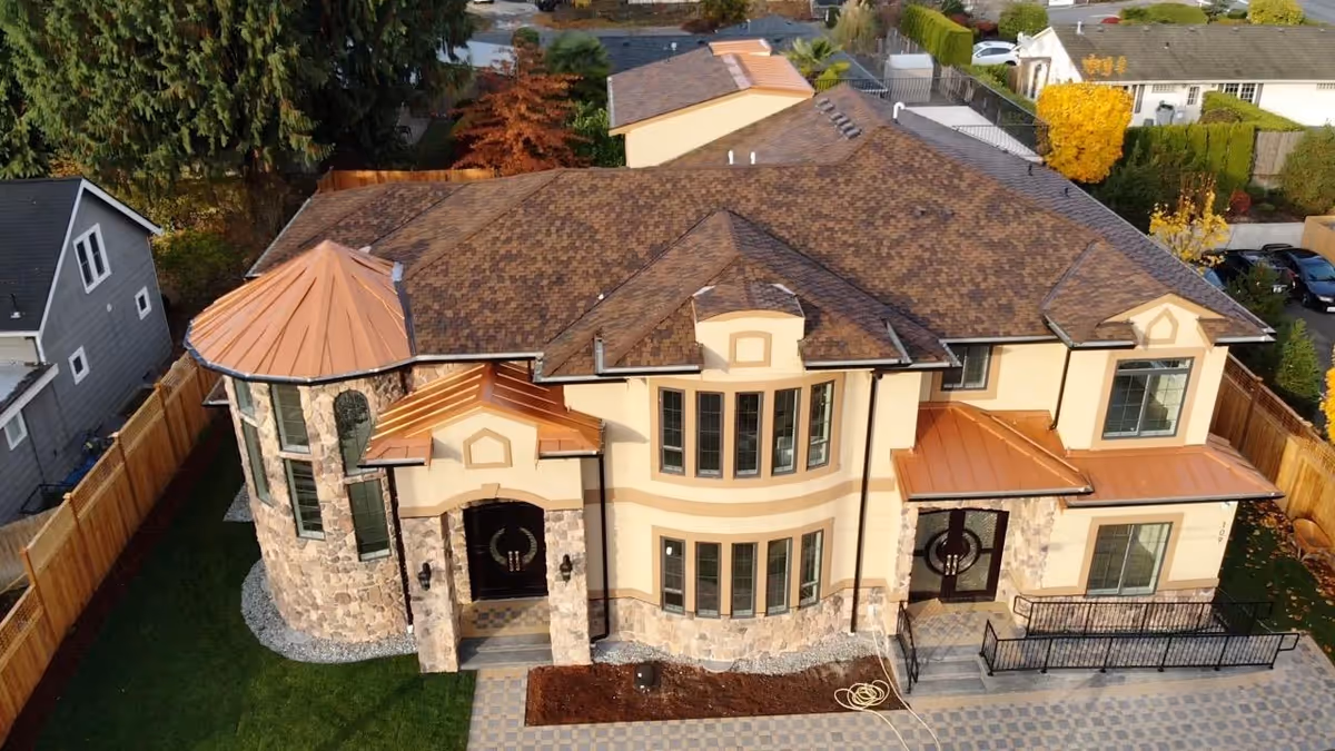 Aerial view of a large tan building with stone accents and a fenced backyard.