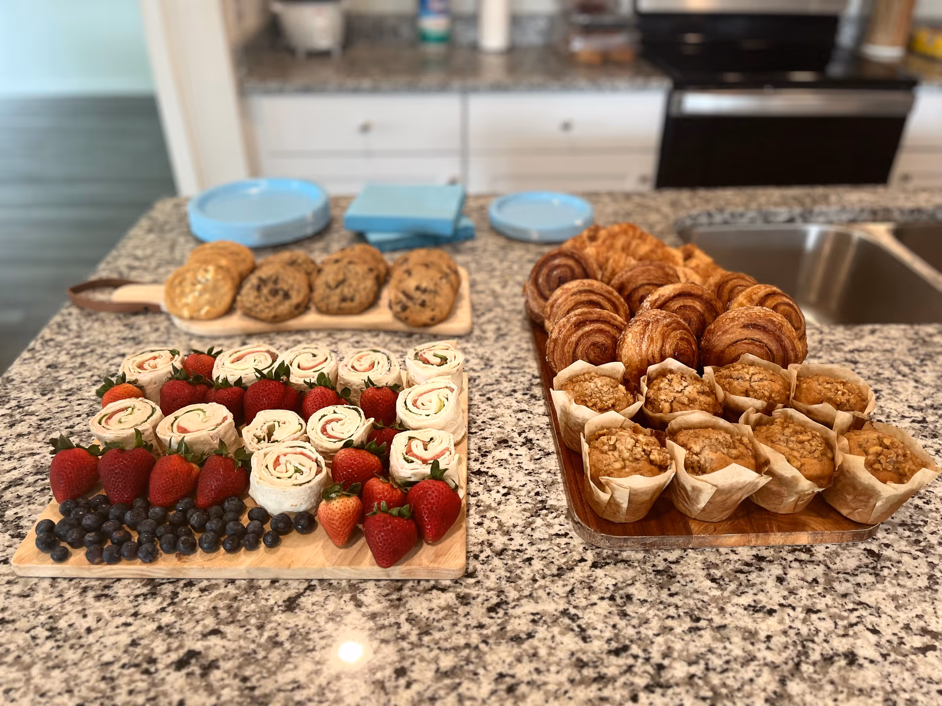 A kitchen island with assorted pastries and fruit on a granite countertop.