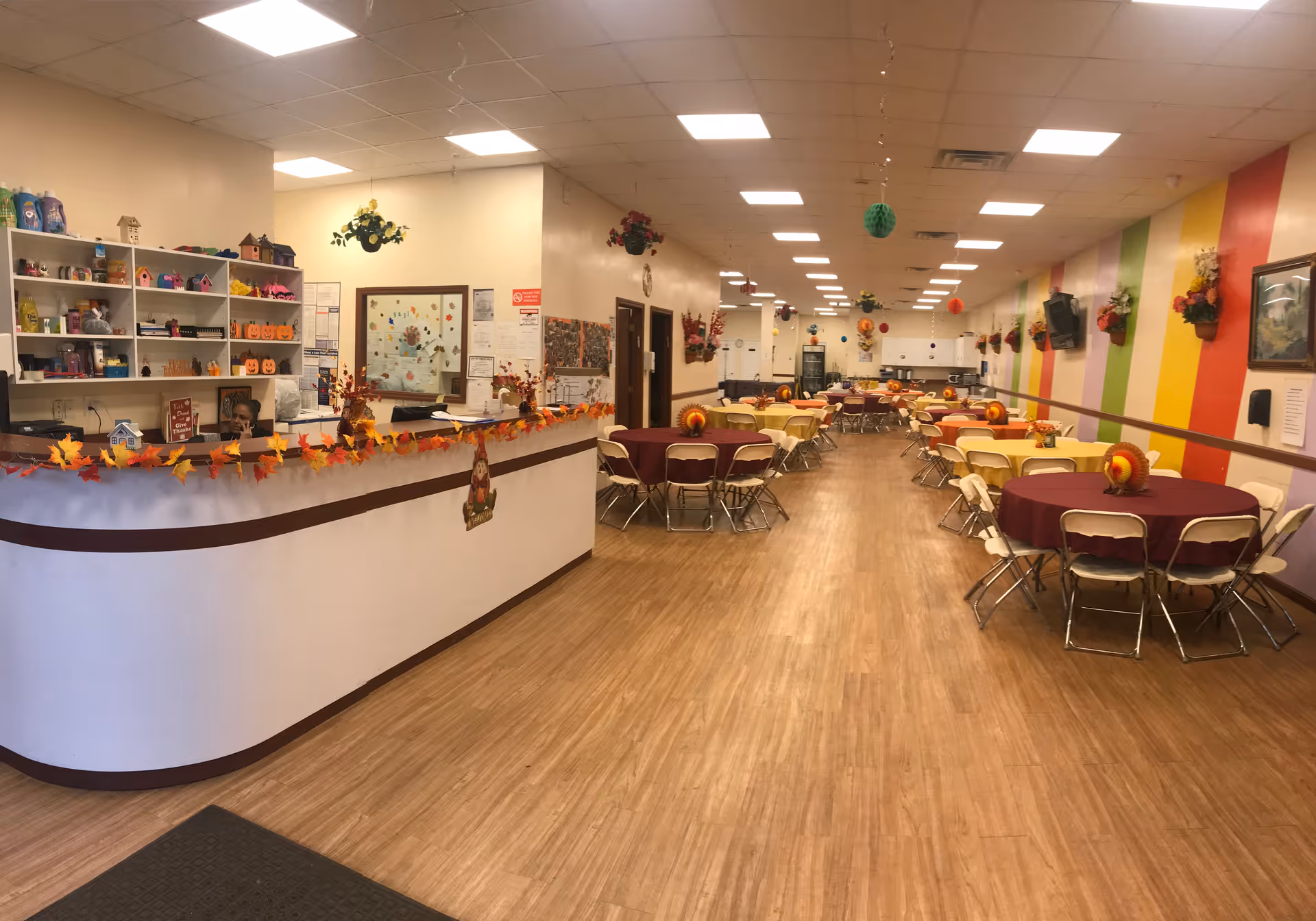 Colorful, well-lit dining hall with round tables and a curved service counter.