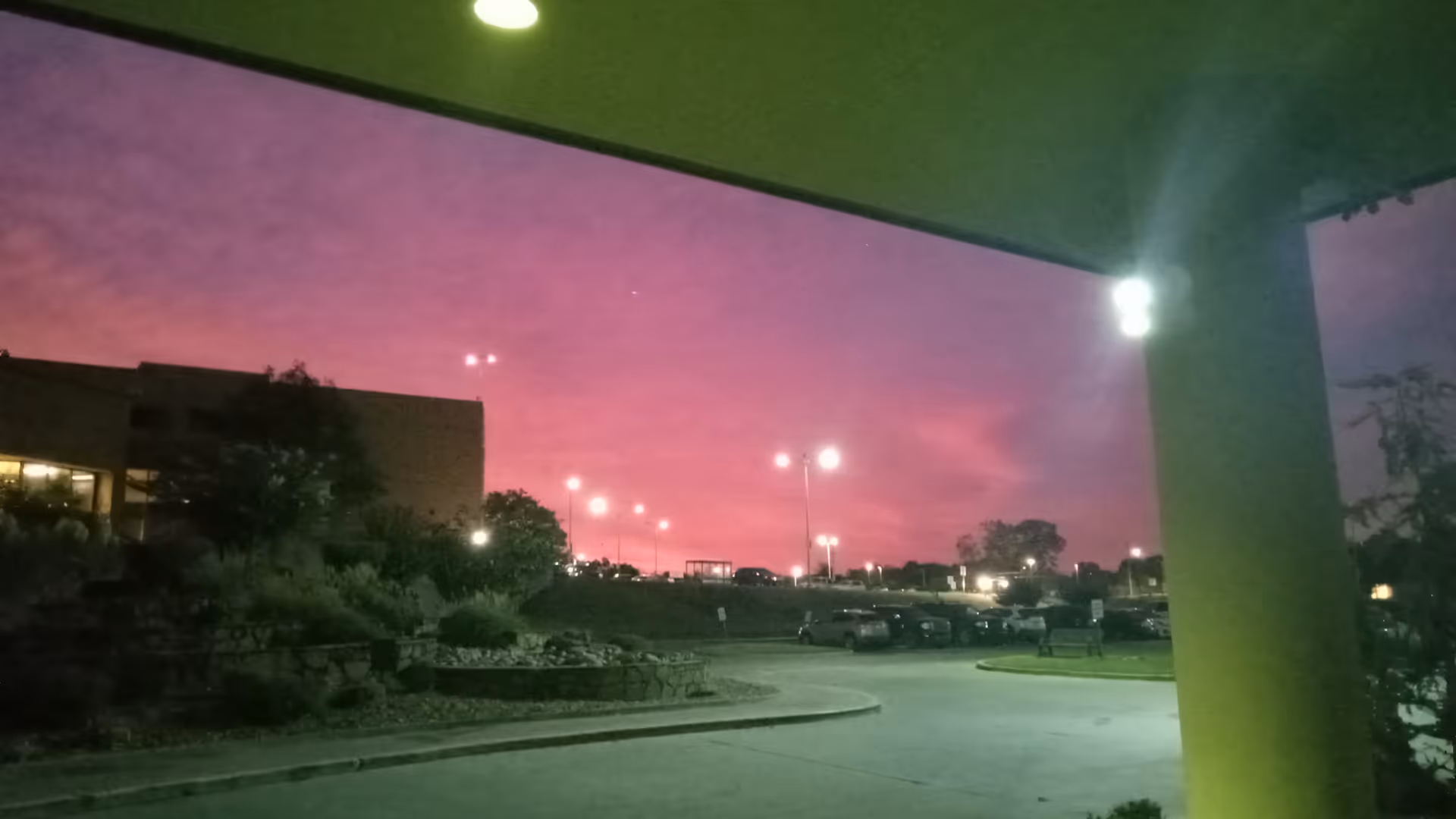 Dusk exterior view of a medical facility with parking lot and pink sky.