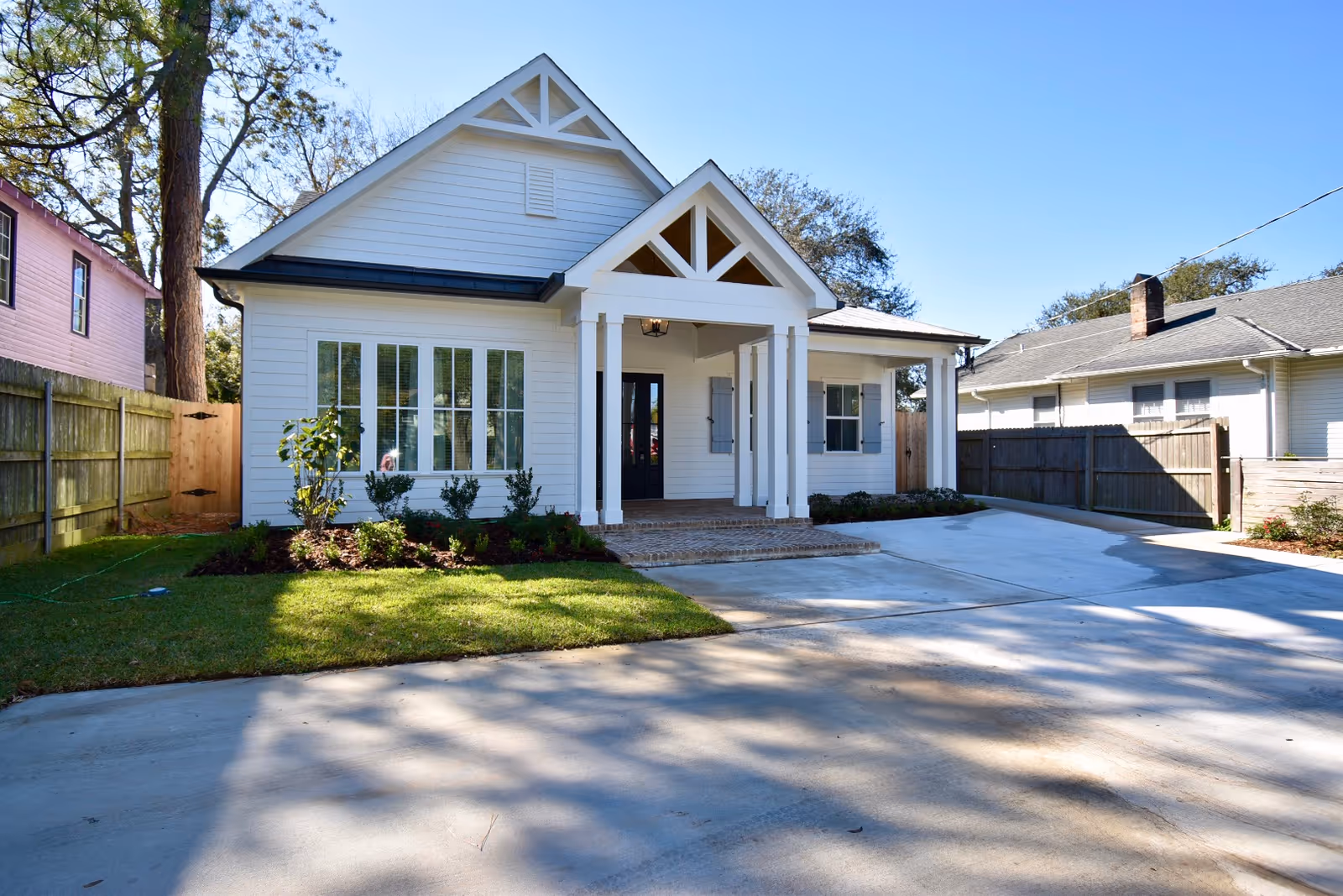 White modern house with a covered front porch and concrete driveway.