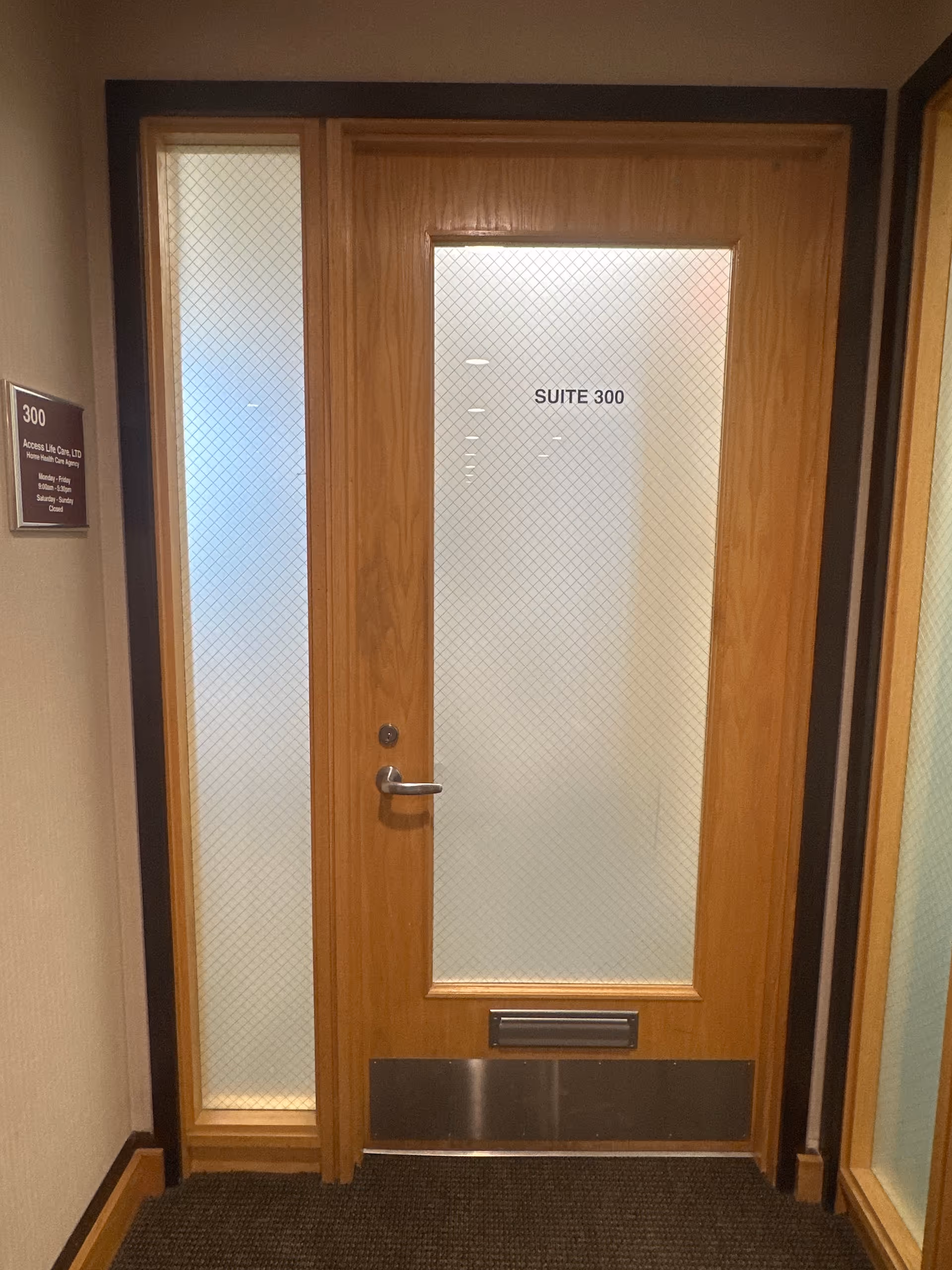 Wooden interior door labeled Suite 300 with frosted glass in a hallway.