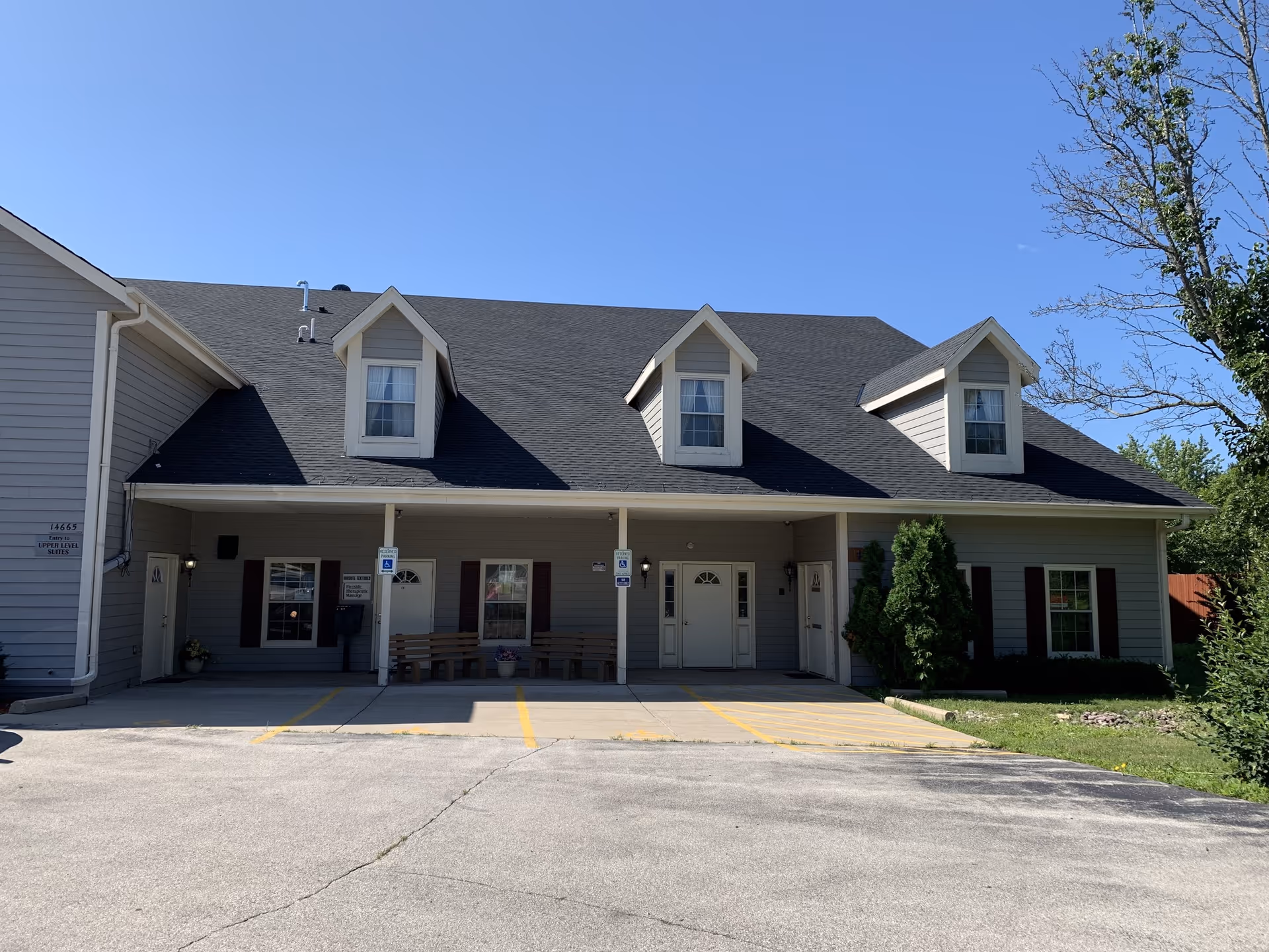 Exterior view of a senior living facility building with front entrances and benches.