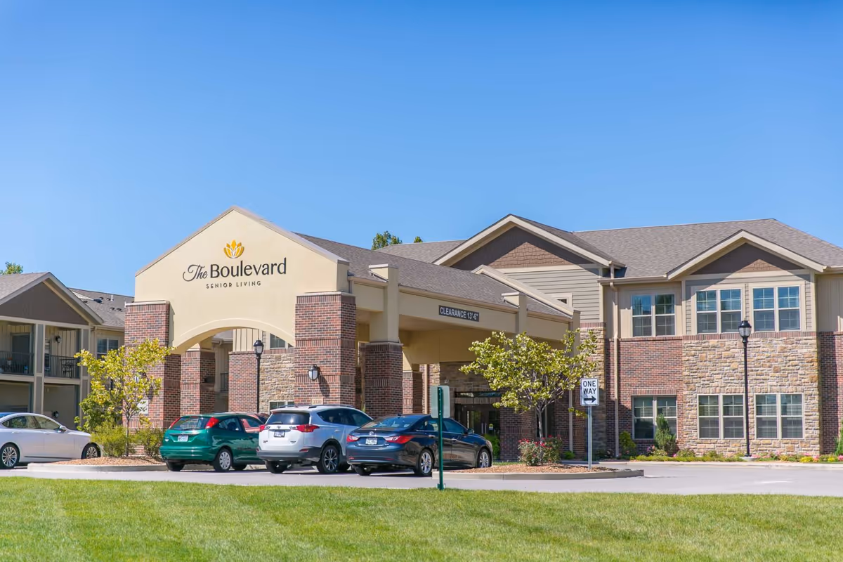 Exterior view of The Boulevard Senior Living facility with parked cars and clear sky.
