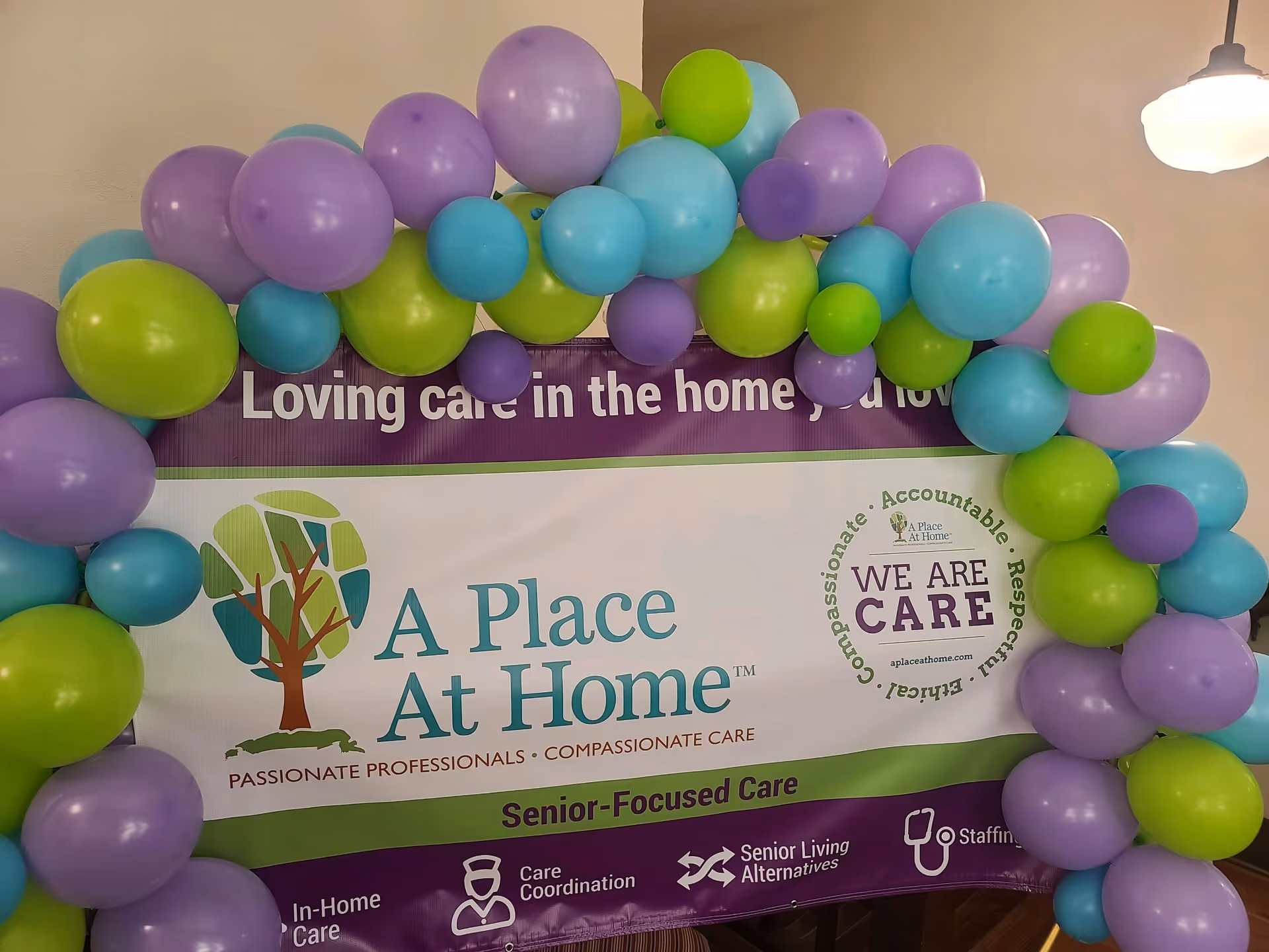 Indoor banner display framed by colorful balloons for A Place At Home.
