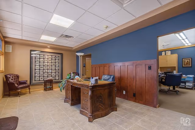 Wood-paneled reception area with a large desk, seating, and framed artwork on tan and blue walls.