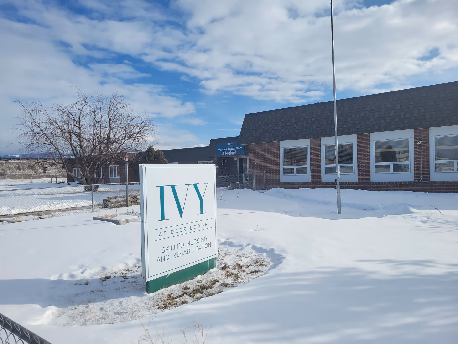 Snowy front exterior of The Ivy at Deer Lodge with a large facility sign