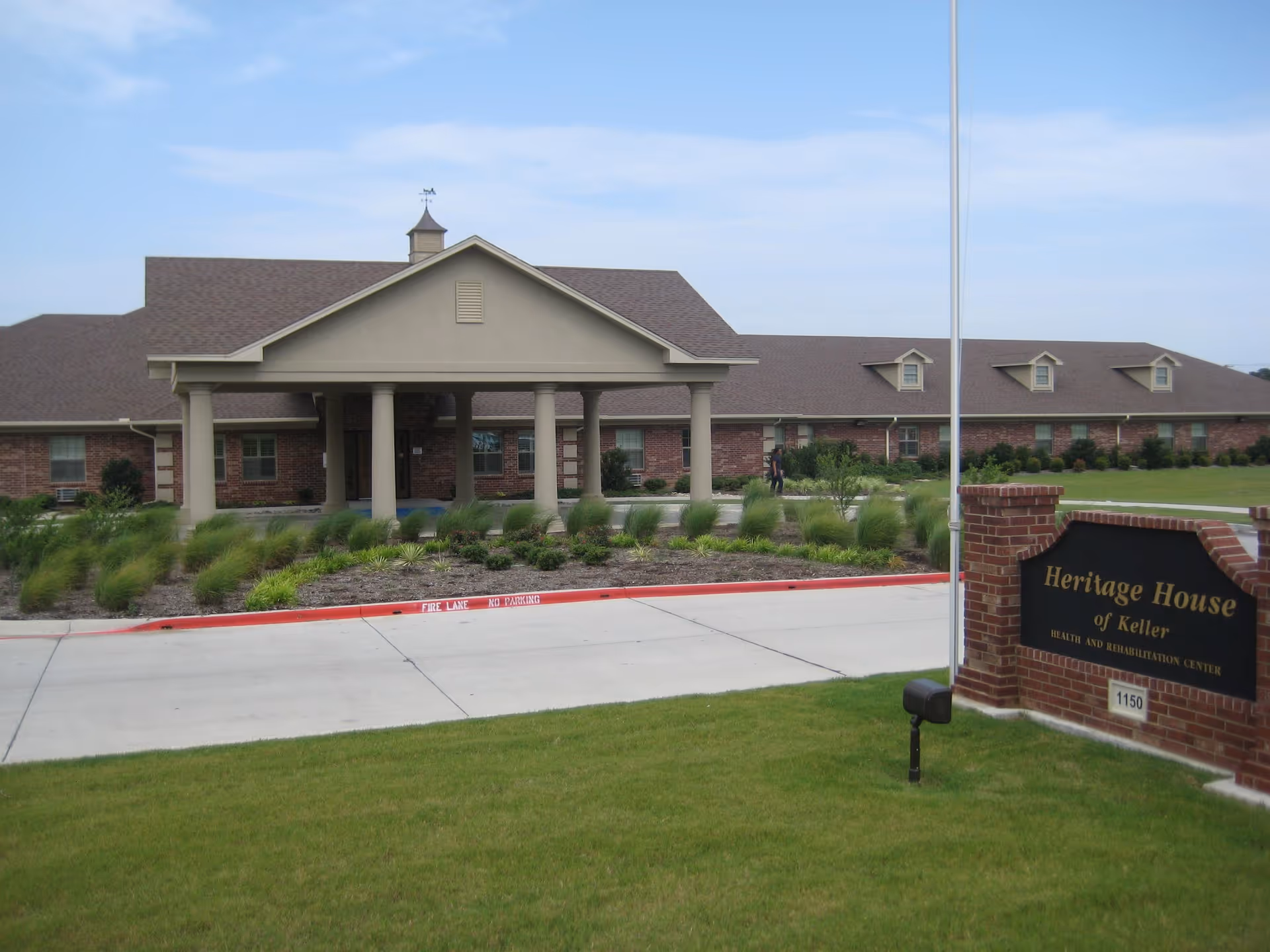 Exterior view of Heritage House of Keller, a brick senior living and rehabilitation facility with portico.