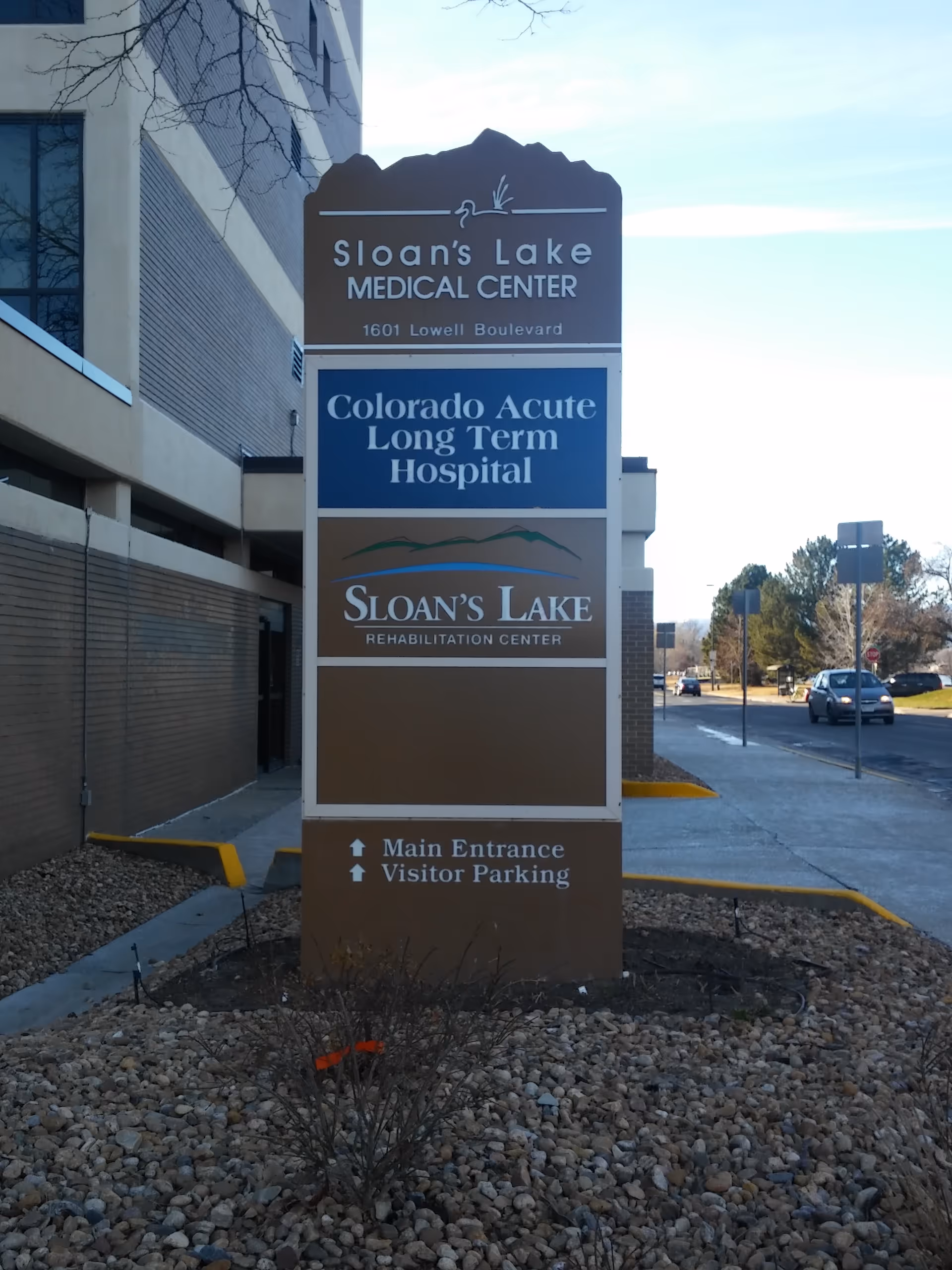 Tall multi-panel sign for Sloan's Lake Medical Center in front of building.