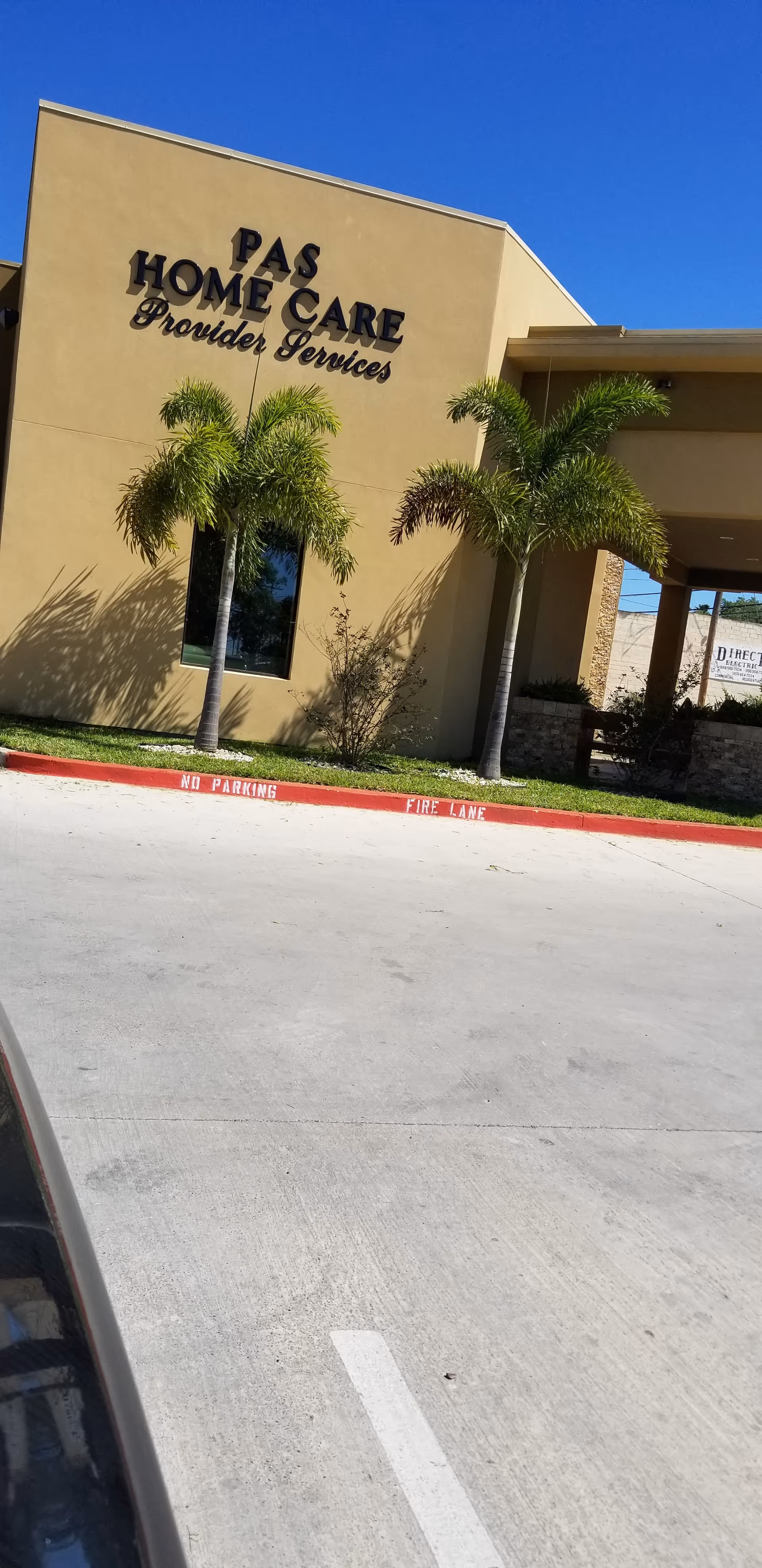 Exterior view of Pas Home Care building with palm trees and a front parking lot.