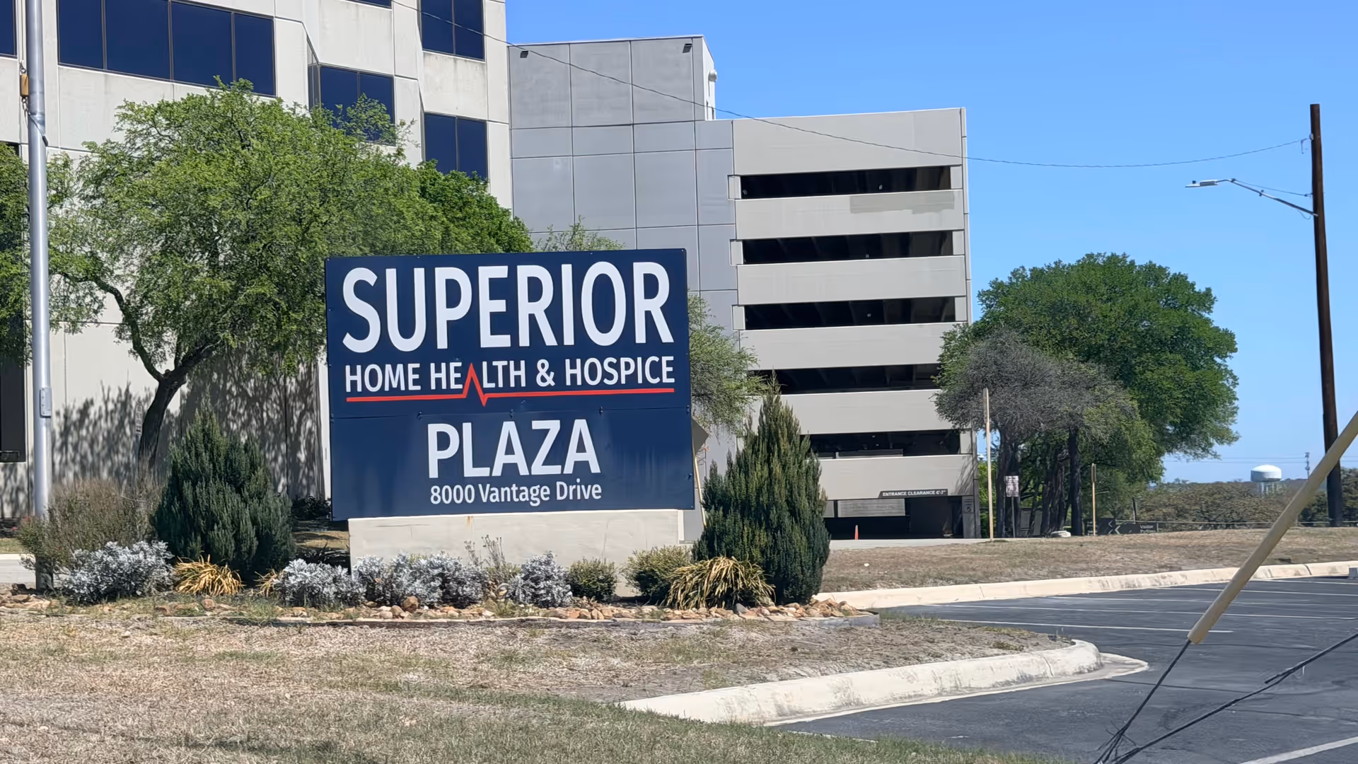 Exterior view of Superior Plaza sign with building and parking garage in background.