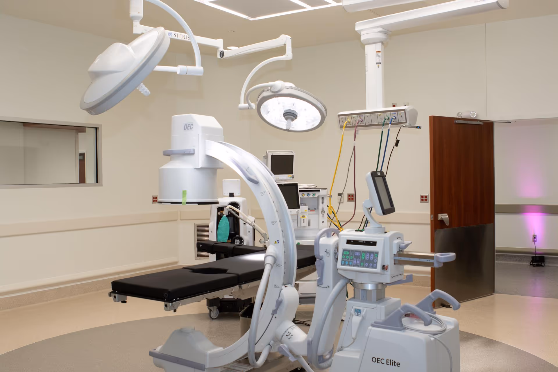 Surgical suite with imaging equipment and overhead lights in a clean hospital operating room.