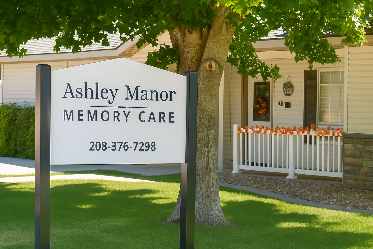 Front exterior of Ashley Manor Memory Care with a large sign and entry porch.