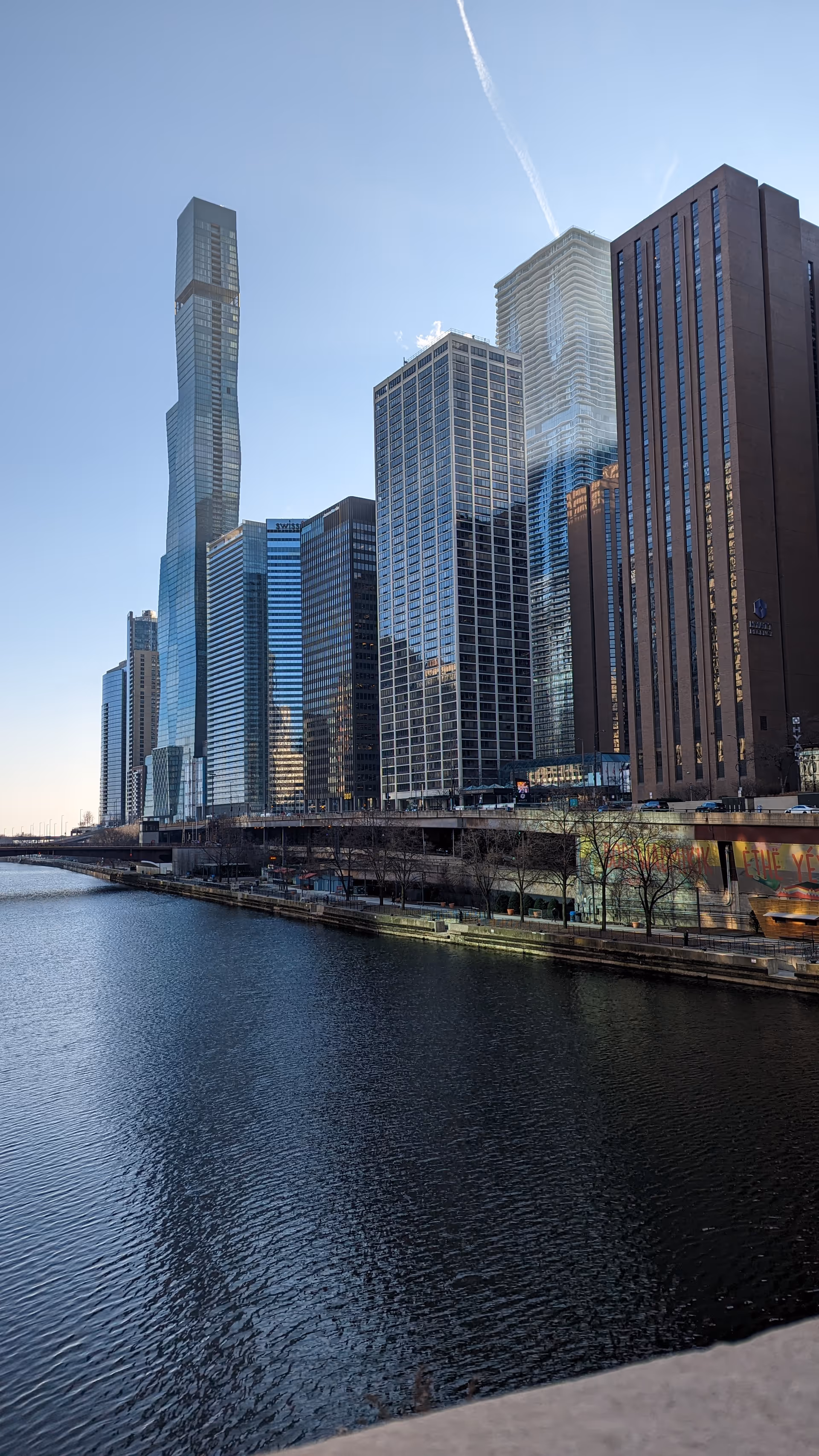 City skyline with glass high-rise towers along a calm riverfront