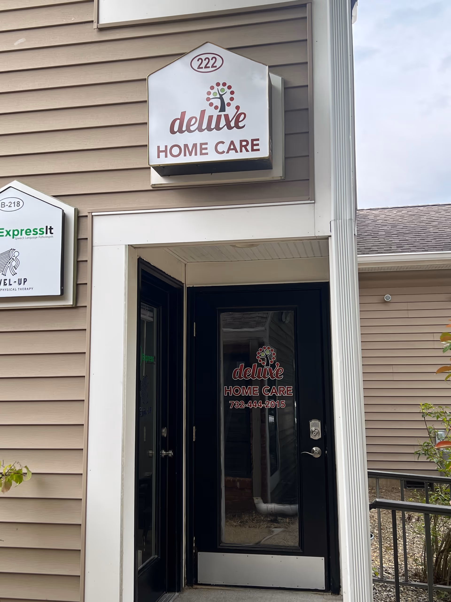 Facade of Deluxe Home Care facility with entrance door and prominent sign