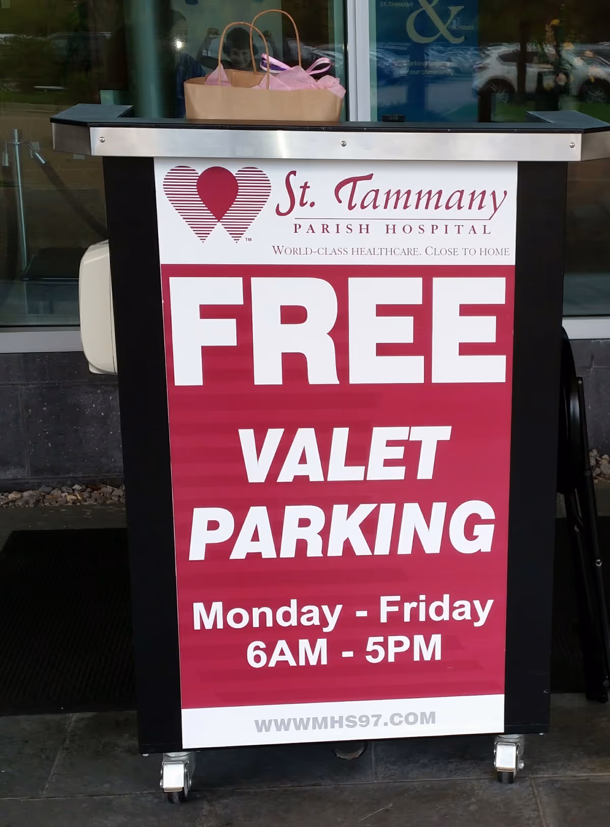 A freestanding sign on wheels outside a hospital entrance advertising free valet parking.