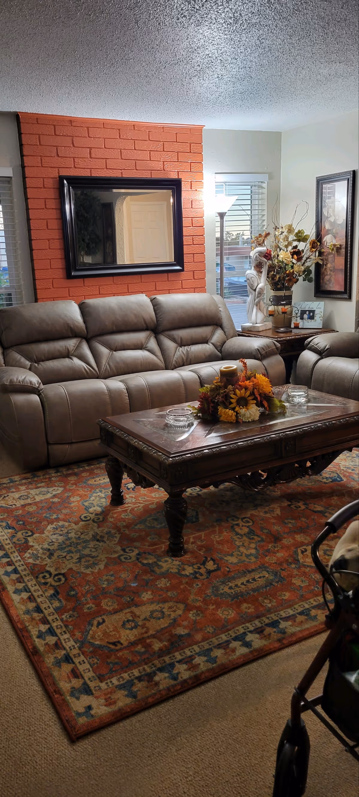 Cozy living room with brown leather sofas, brick accent wall, and autumn decor.