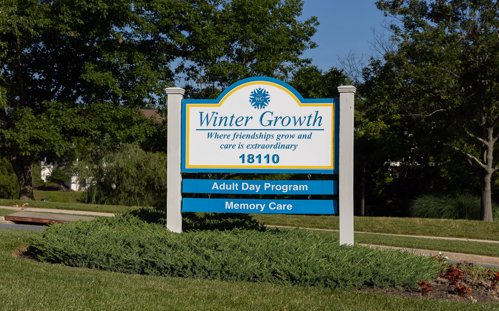 Outdoor sign for Winter Growth Memory Care surrounded by greenery and trees.