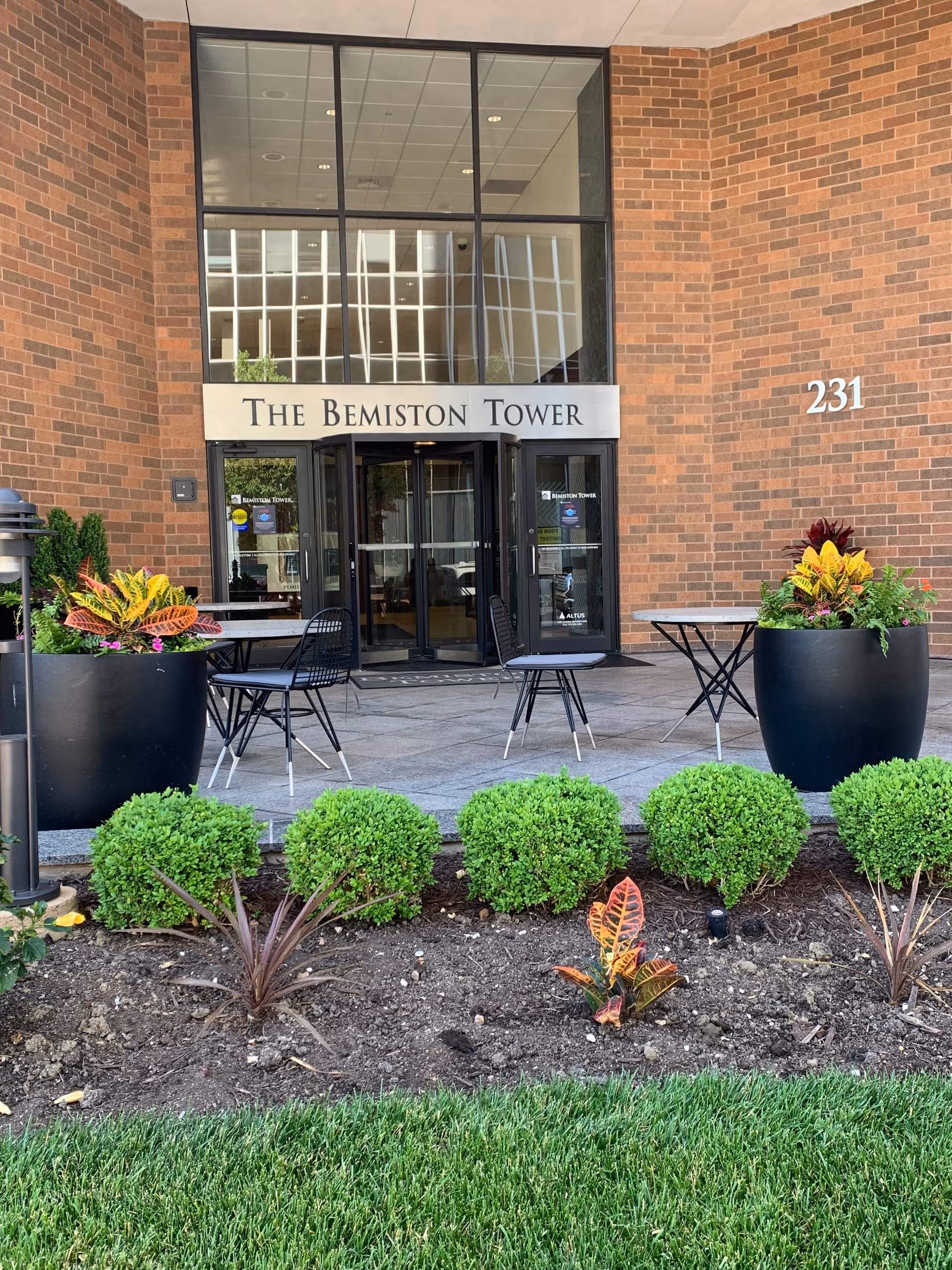 Exterior entrance to The Bemiston Tower with outdoor tables, chairs, and planters.