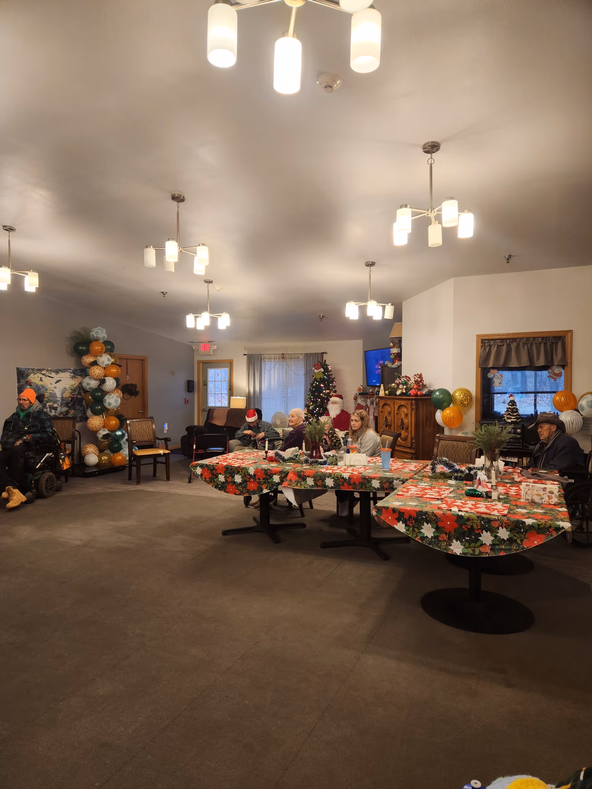 Residents gather around festively decorated tables in a holiday-themed dining room.