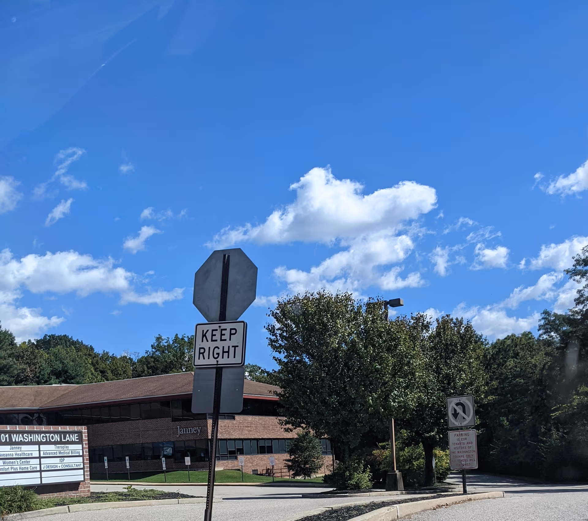 Blue sky above a brick building with a stop sign and street signs.