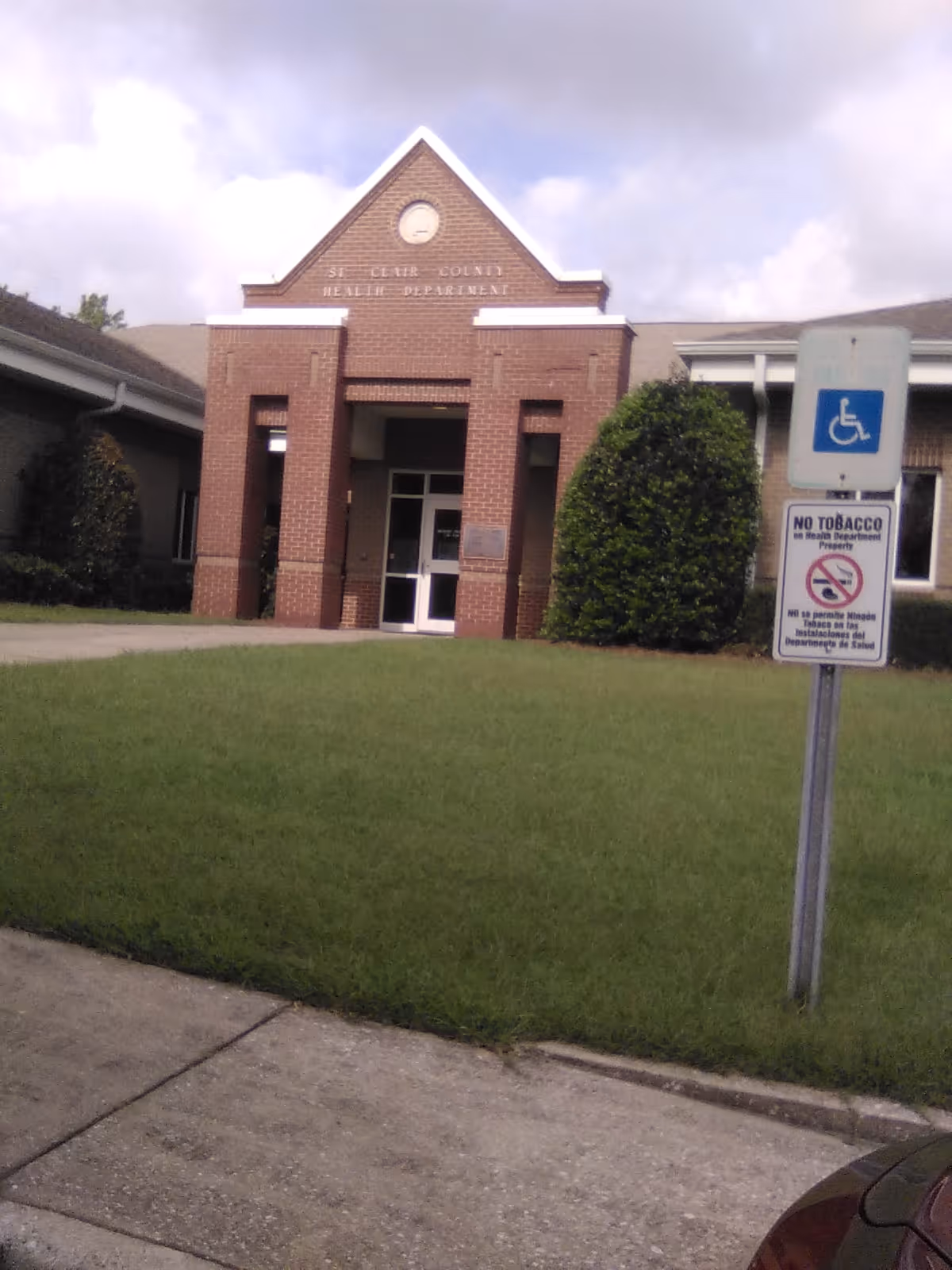 Front of St. Clair County Health Department building with entrance and handicapped parking sign