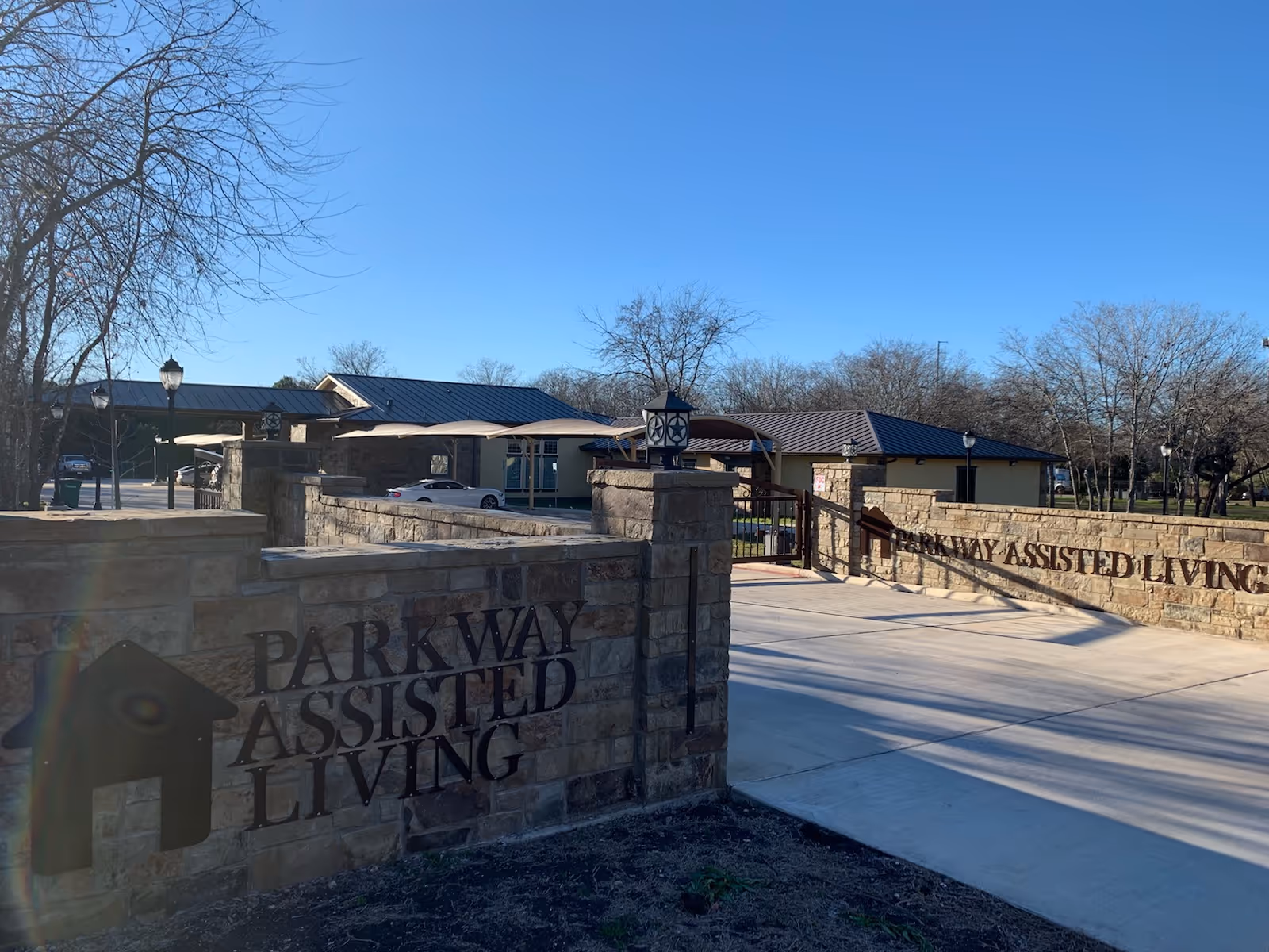 Stone entrance wall reads Parkway Assisted Living with a driveway leading to the facility buildings.