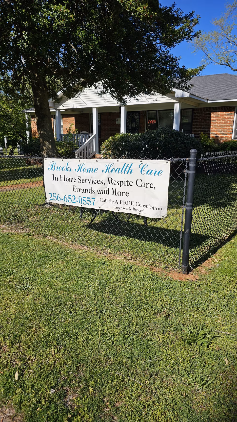 Front view of a brick facility with a chain-link fence and Brooks Home Health Care banner