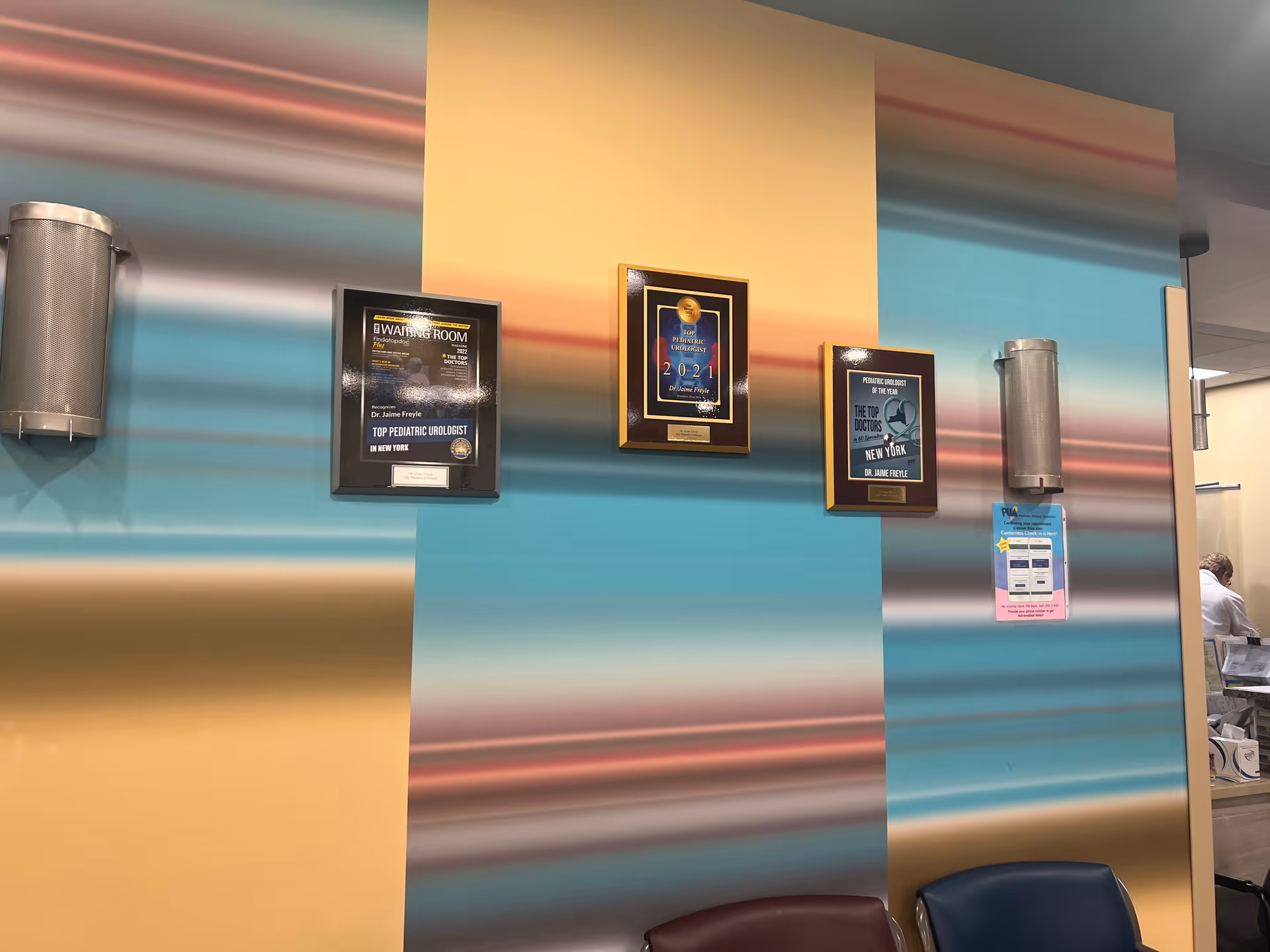 Colorful striped wall with framed awards and seating in a hallway interior.