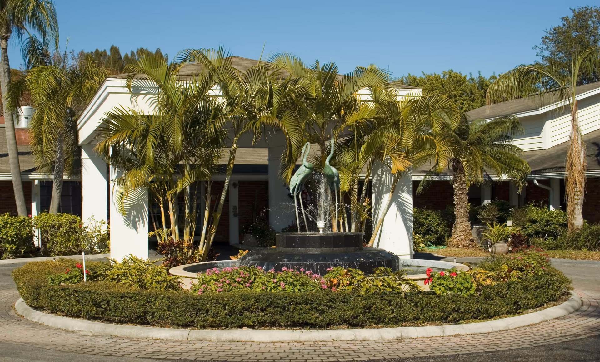 Baytree Lakeside entrance with a circular fountain, palm trees, and surrounding landscaping.