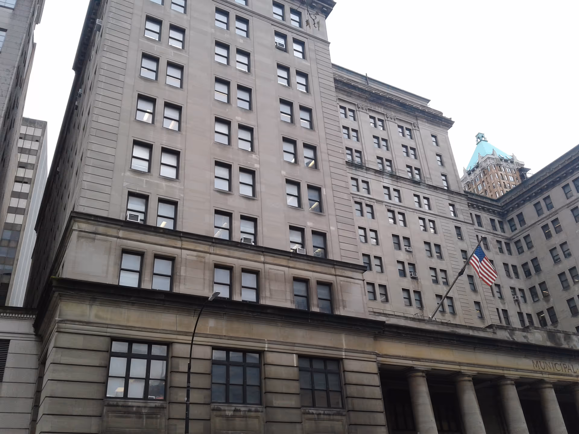 Tall gray stone government building with columns and an American flag
