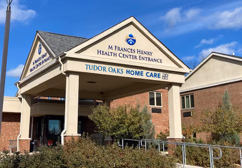 Front exterior of Tudor Oaks Home Care entrance with signage and landscaping.