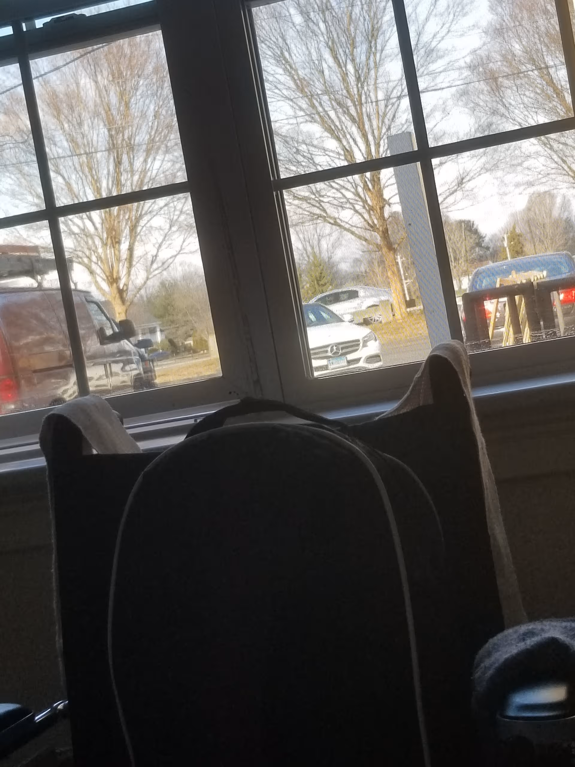 An interior room with a large window, view of parked cars outside, and a dark chair.