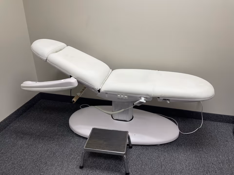 White medical examination chair in a treatment room with a small step stool