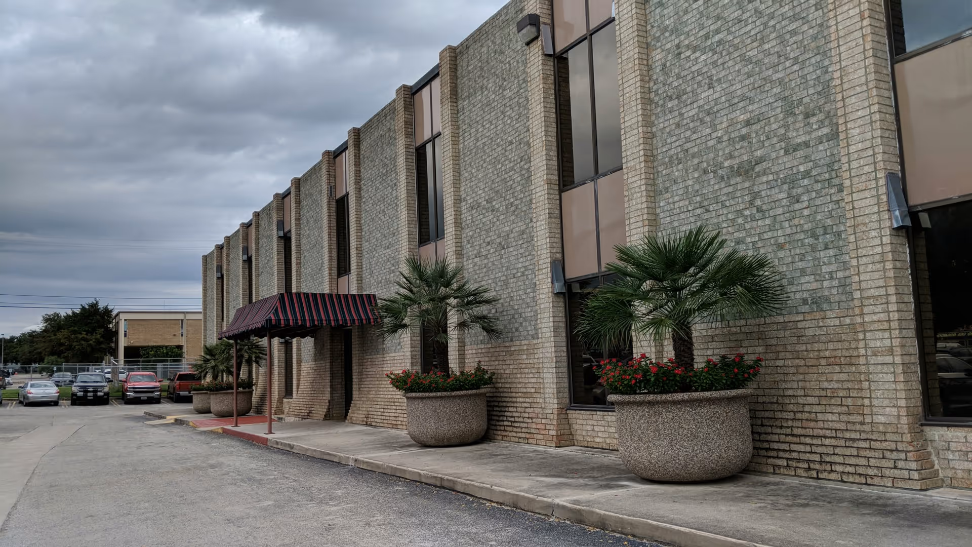 Exterior view of Cardinal Senior Care building with brick facade, planters, and entrance canopy.