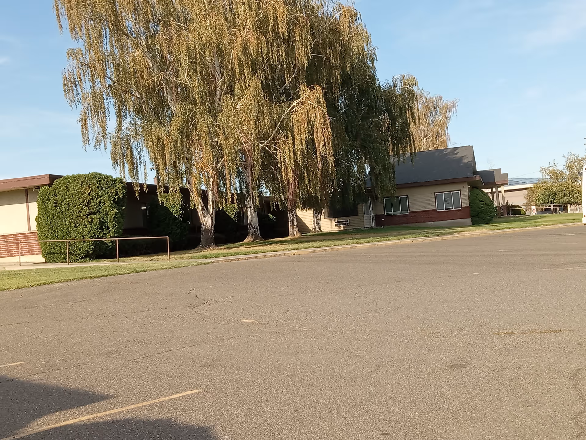 Exterior view of a single-story facility with trees and shrubs in front.
