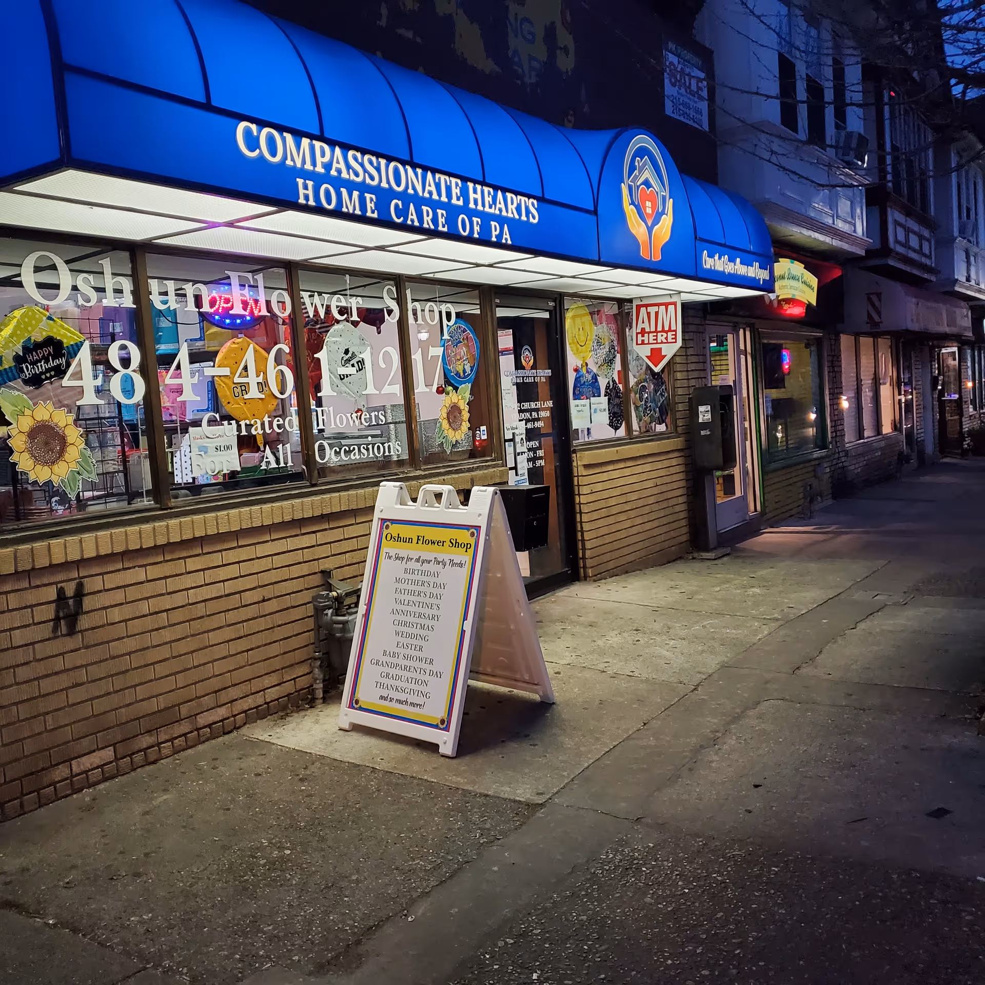Blue storefront sign for Compassionate Hearts Home Care of PA above a flower shop.