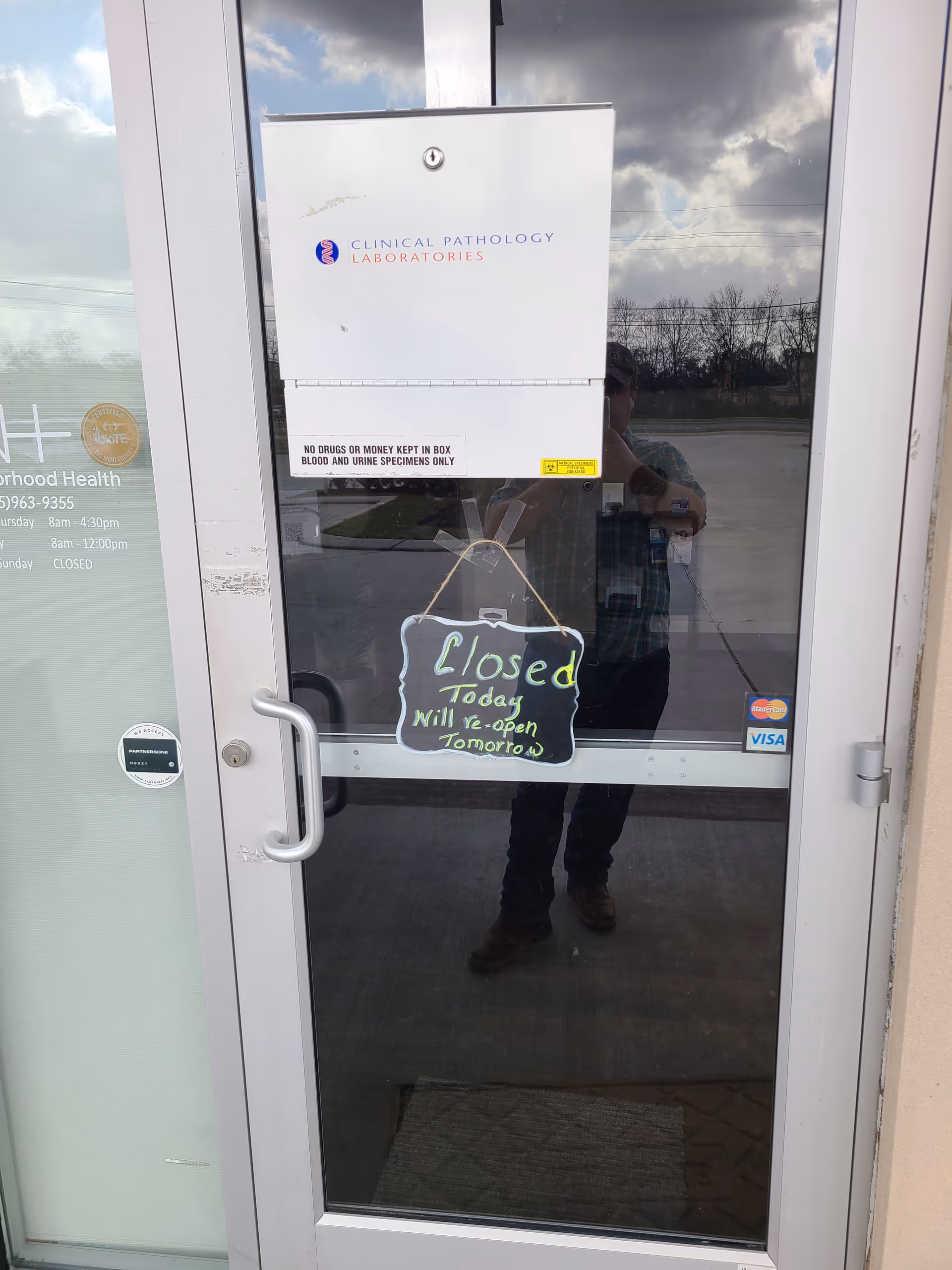 Glass entrance door with a 'Closed today' sign and a reflected person.
