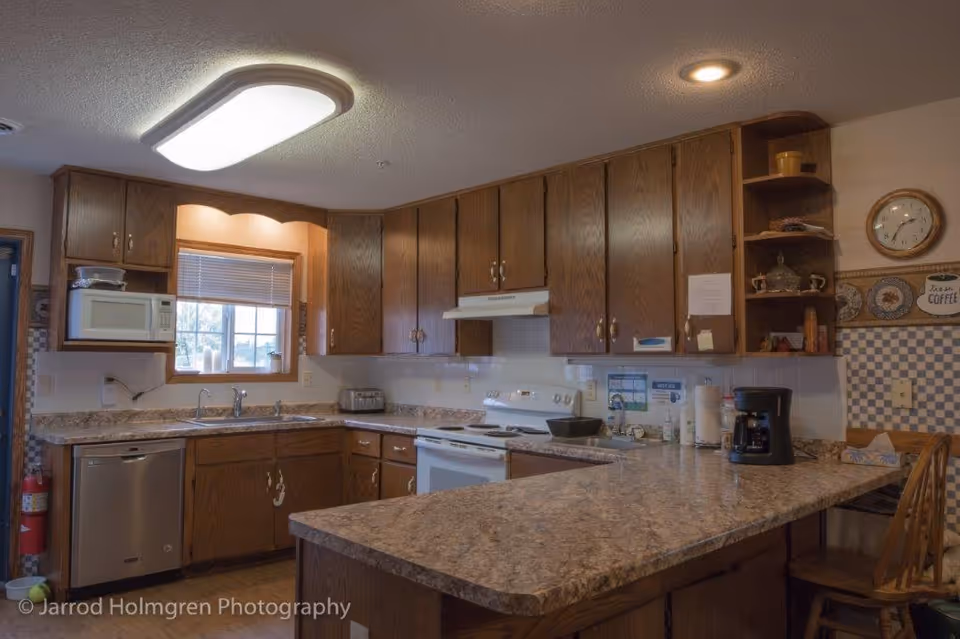 Wood-paneled kitchen with a large island countertop, sink, stove, microwave, and coffee maker.