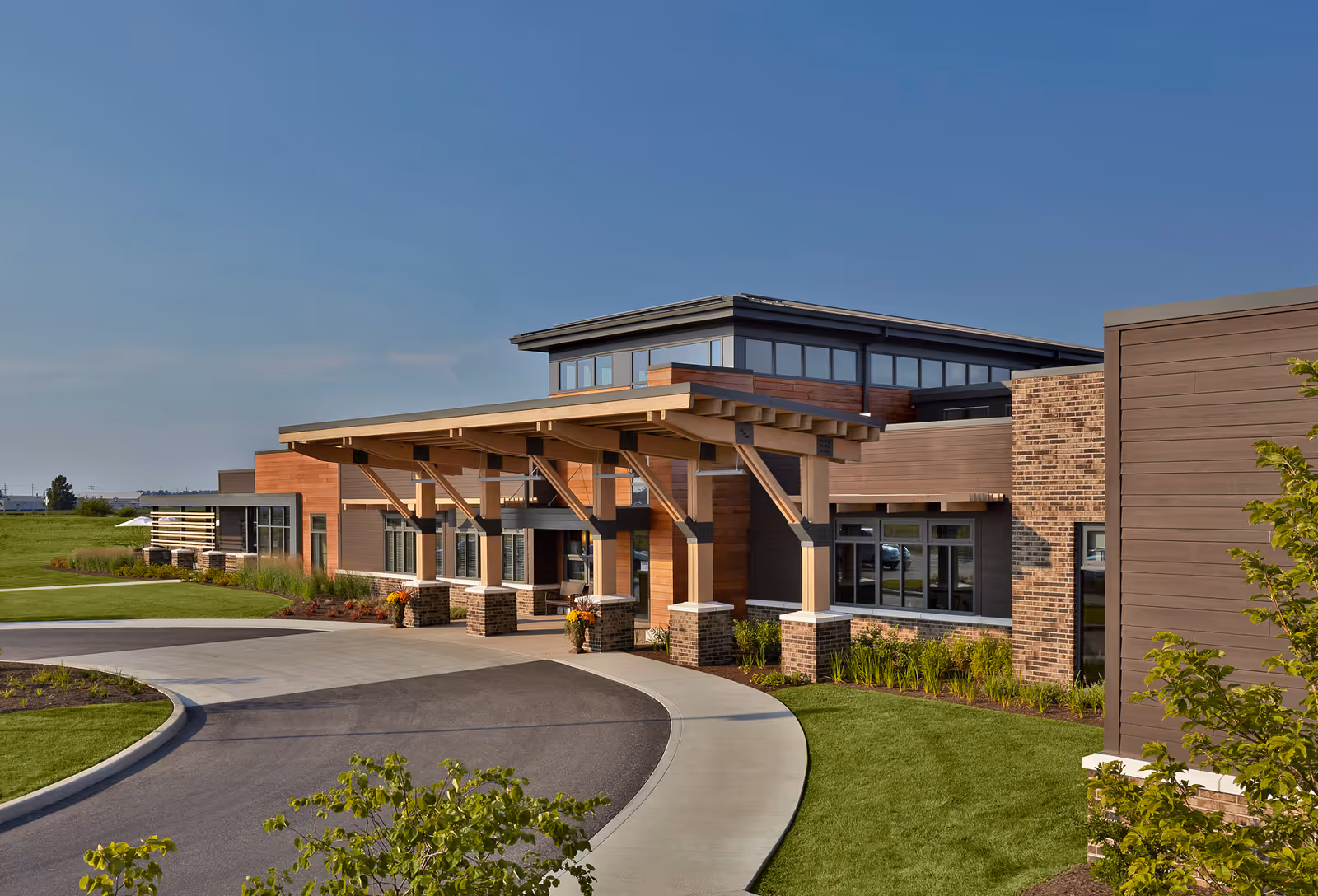 Modern senior living facility exterior with curved driveway and covered entrance.