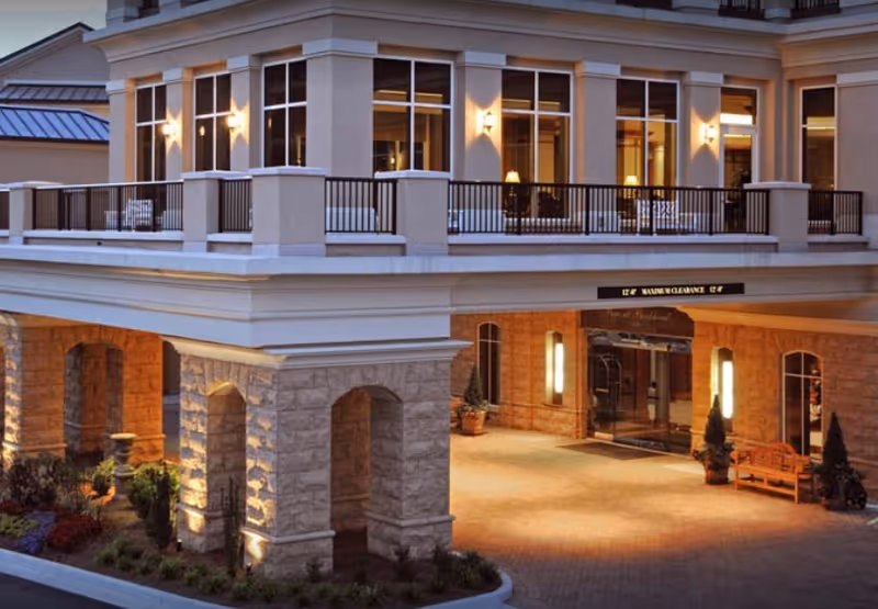 Exterior view of The Piedmont at Buckhead with lit entrance and second-floor balcony.