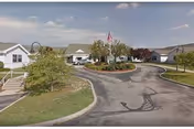 Exterior view of a senior living campus with a circular driveway and flagpole.