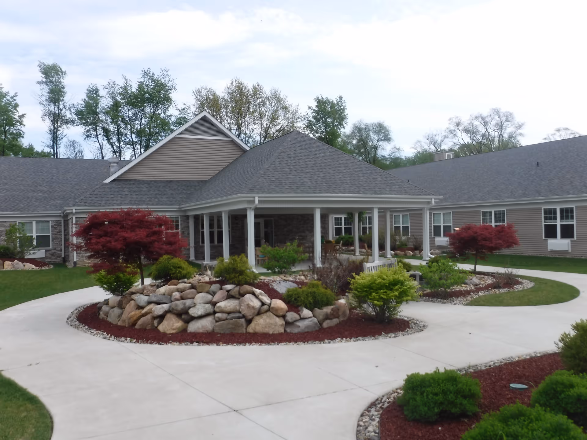 Senior living facility exterior with circular driveway and landscaped entrance.