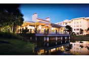 Twilight view of Cypress Cove senior living exterior with a lit terrace over a reflecting canal.