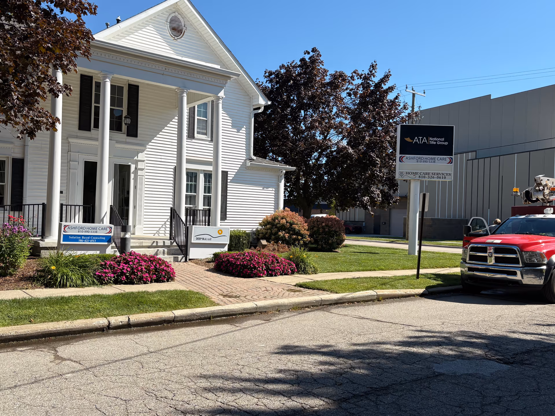 White colonial-style building with columns, manicured landscaping, and Ashford Home Care signage.